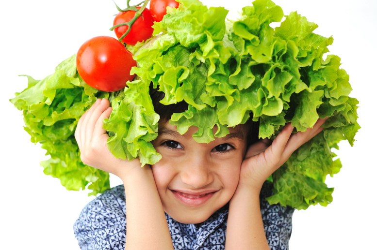 Kid with salad and tomato hat on his head, fake hair made of veg